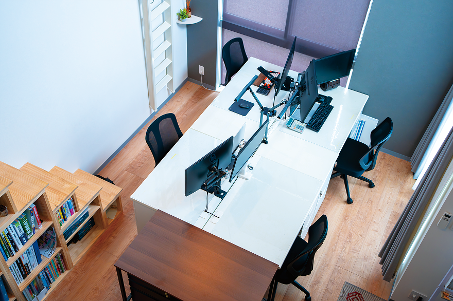 白いデスクにモニターと椅子が配置されたオフィスの俯瞰写真